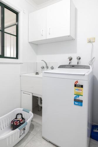 a white kitchen with a sink and a mirror at Nautilus Nest - Port Sorell in Port Sorell