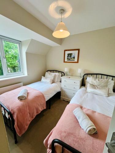 a bedroom with two beds and a dresser in it at Hideaway Cottage in Bourton on the Water