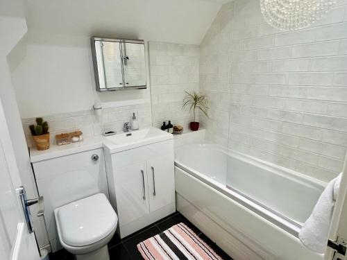 a bathroom with a toilet and a tub and a sink at Hideaway Cottage in Bourton on the Water