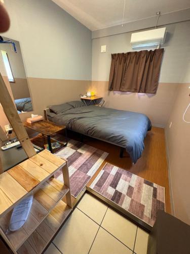 ein kleines Zimmer mit einem Bett und einem Tisch in der Unterkunft beach house in Amami