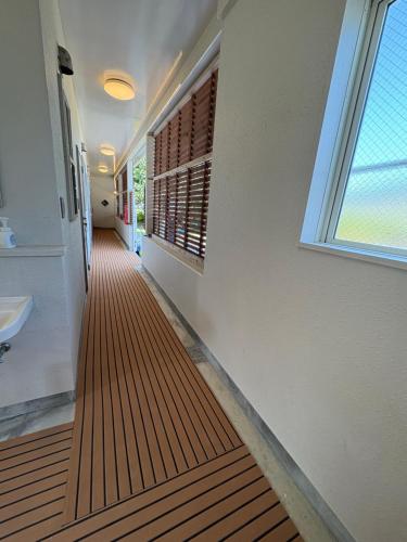 ein Flur vor einem Badezimmer mit Waschbecken und Fenster in der Unterkunft beach house in Amami