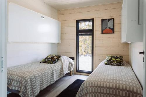two beds in a room with a window at Stay North - Villa Mono in Pälkäne