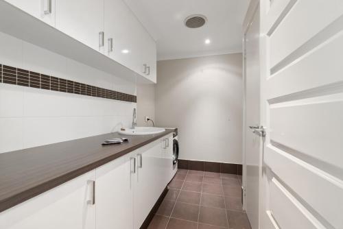 a white bathroom with a sink and a washing machine at The Grand Aveley House in The Vines
