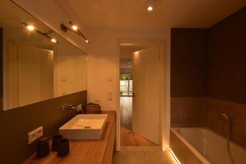 a bathroom with a sink and a tub and a mirror at Das Alpiente - Das Urlaubshaus im Allgäu in Sonthofen