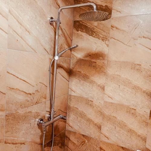 a shower in a bathroom with a stone wall at Zaga Bloom Apartment in Banja Koviljača