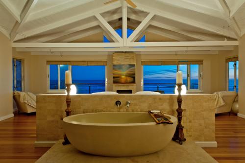 a large bathroom with a large tub in front of a bedroom at Dune Rose in Yzerfontein