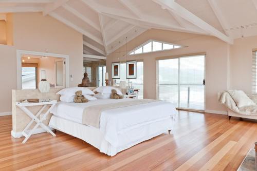 a large white bedroom with two teddy bears sitting on a bed at Dune Rose in Yzerfontein