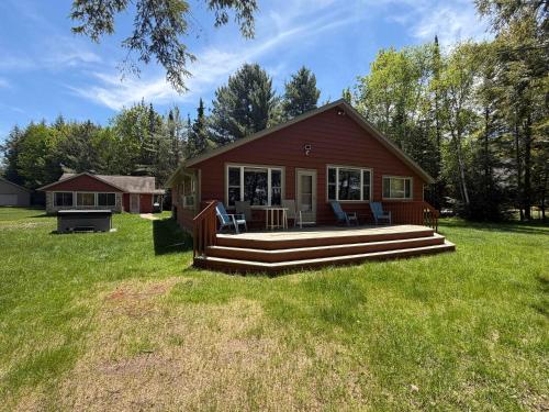 a small red house with a porch and a deck at Watermelon Retreat & Suite in Three Lakes