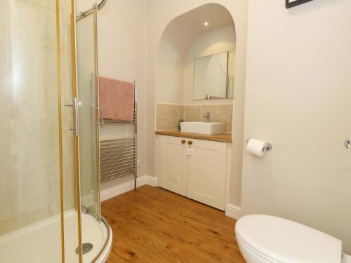 a bathroom with a shower and a toilet and a sink at Sea Pink Cottage in Swanage