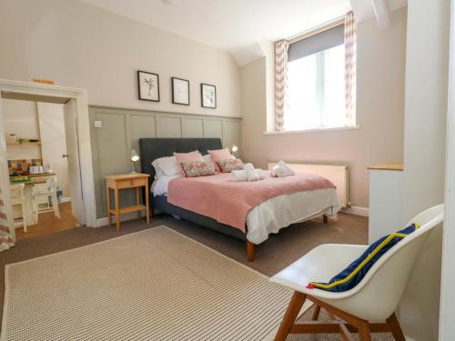 a bedroom with a bed and a window and a chair at Sea Pink Cottage in Swanage
