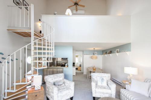 a living room with a staircase and chairs at Coastal Cozy in Brewster