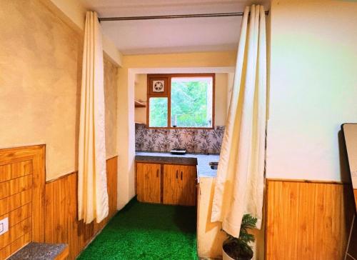 a kitchen with a green floor and a window at Jamming Tree in Manāli