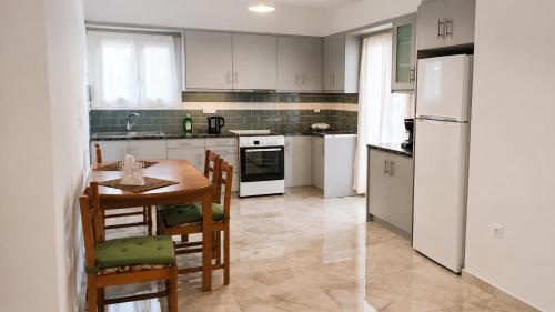 a kitchen with white appliances and a table and chairs at Azalea Guesthouse in Andros