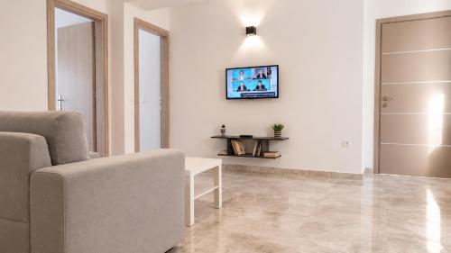 a living room with a couch and a tv on the wall at Azalea Guesthouse in Andros