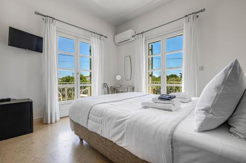 a white bedroom with a large bed and windows at Mimoza in Spetses