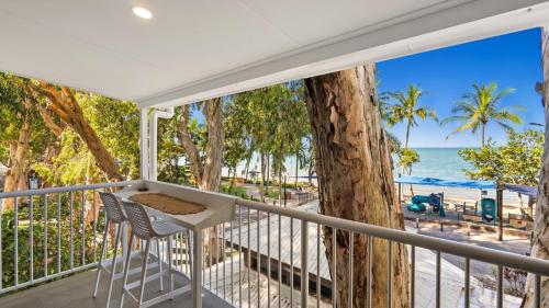 a balcony with a table and chairs and the beach at Absolute Beachfront Studio with Pool and Ocean Views in Palm Cove