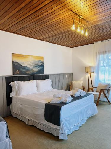 a bedroom with a large bed with a wooden ceiling at Casa Capivari Boutique in Campos do Jordão