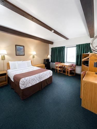 a hotel room with a large bed and a table at Aisling Suites in Great Falls