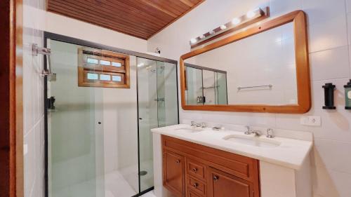 a bathroom with a sink and a shower and a mirror at Casa Capivari Boutique in Campos do Jordão