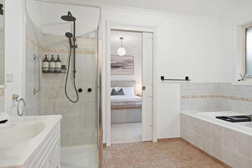 a bathroom with a shower and a tub and a sink at Stylish West Hobart Villa in West Hobart