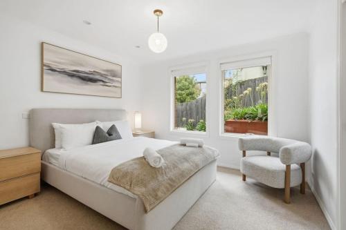 a bedroom with a bed and a chair and a window at Stylish West Hobart Villa in West Hobart