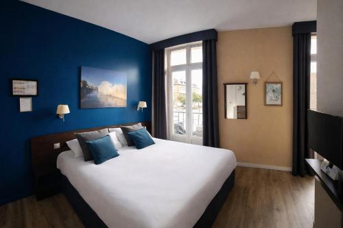 a bedroom with a large bed with blue walls at Hôtel de Bretagne Dol centre ville - Hotel et Restaurant in Dol-de-Bretagne