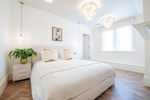 a white bedroom with a large bed and a potted plant at The Carre Arms Hotel & Restaurant in Sleaford