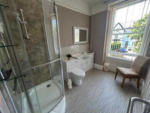 a bathroom with a shower and a toilet and a sink at The Westbourne Guest House in Llandudno