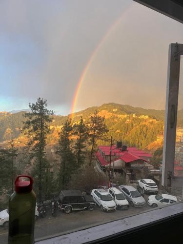 a rainbow over a parking lot with a bunch of cars at Wonder View in Shimla