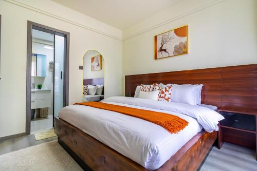 a bedroom with a large bed with a wooden headboard at Luxury 1 bedroom in Westlands, Rooftop Pool, Next to Kempinski & GTC, Fast Wifi & Pool Table in Nairobi