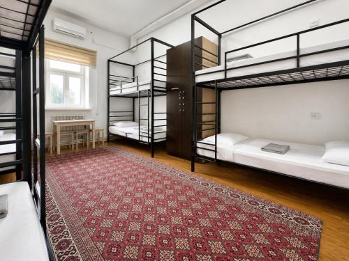 a room with three bunk beds and a rug at Station Hostel in Atyrau