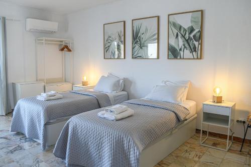 two beds in a room with three pictures on the wall at Casa Dos Amigos in Budens