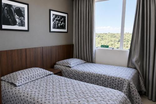 a hotel room with two beds and a window at Barretos Park Hotel in Barretos