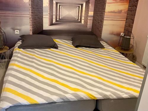 a large bed with yellow and white stripes in a room at Le Gîte de Brigitte ! in Saint Die