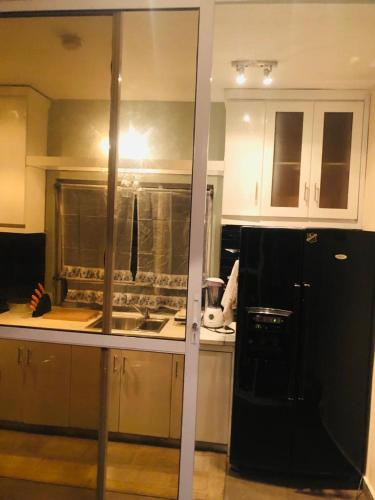 a kitchen with white cabinets and a black refrigerator at Sandvica Luxe Homes in Port Harcourt