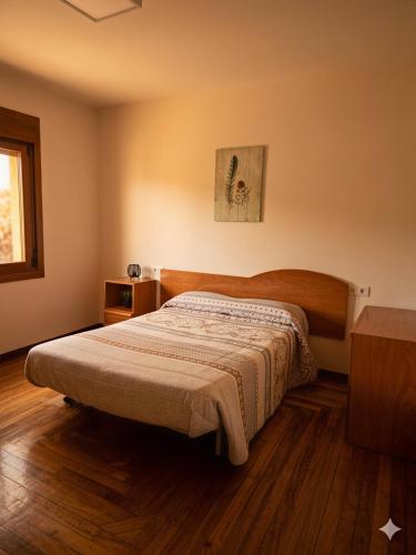 a bedroom with a bed and a wooden floor at A Veiga Grande in Pontevedra