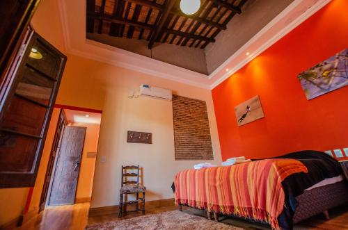 a bedroom with orange walls and a bed and a ladder at Nido de Pajaros Posada Boutique in Concepción