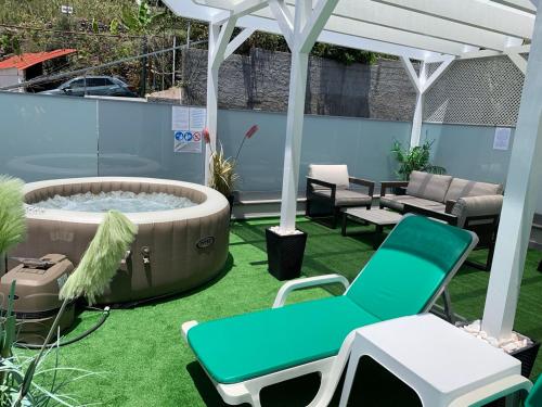 a patio with a hot tub and chairs on the grass at VILLA HELENA Crystal Apartment in Caniço