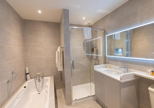 a bathroom with a tub and a sink and a shower at The Tides Ballybunion in Ballybunion