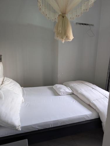 a bed in a room with white sheets and curtains at Nandyowa Guesthouse in Kampala