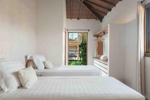 two beds in a white room with a window at Odoyá Casa Hotel in Paraty