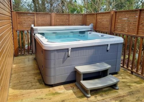a hot tub on a deck with a step stool at Devon Comfort Lodge with Hot Tub - Spa Resort in Devon in Chudleigh