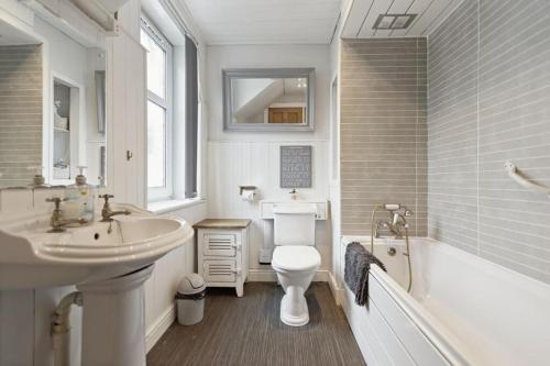 a bathroom with a sink and a toilet and a tub at Dunella Traditional Cottage in Callander