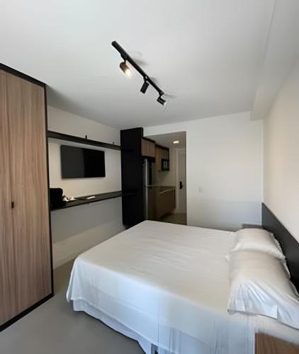 a bedroom with a white bed and a flat screen tv at Studio 809 | Luxo e Novo | SP Expo, metrô e Itaú in São Paulo
