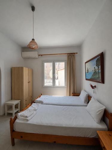 a bedroom with two beds and a window at Iliada Skiathos rooms in Skiathos