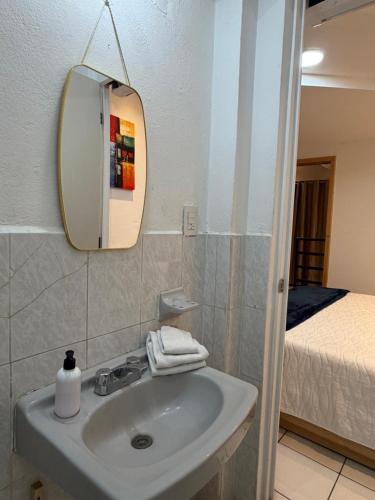 a bathroom with a sink and a mirror and a bed at Suites Xico Oaxaca in Oaxaca City