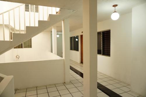 a staircase in a white house with a hallway at Hotel Los Proceres in La Aurora
