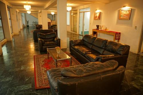 a living room with two leather couches and a table at Hotel Los Proceres in La Aurora