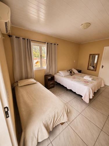 a bedroom with two beds and a window at Pousada Arcanjo Rafael in Urubici