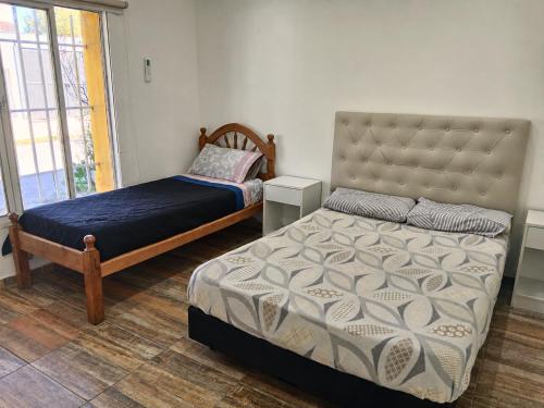 a bedroom with two beds and a large window at Depto Manzur in Villa Mercedes